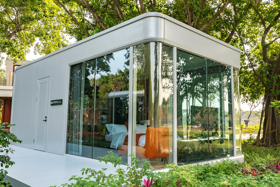 Modular granny flat exterior in daylight showing rounded aluminum corners and panoramic glass facade
