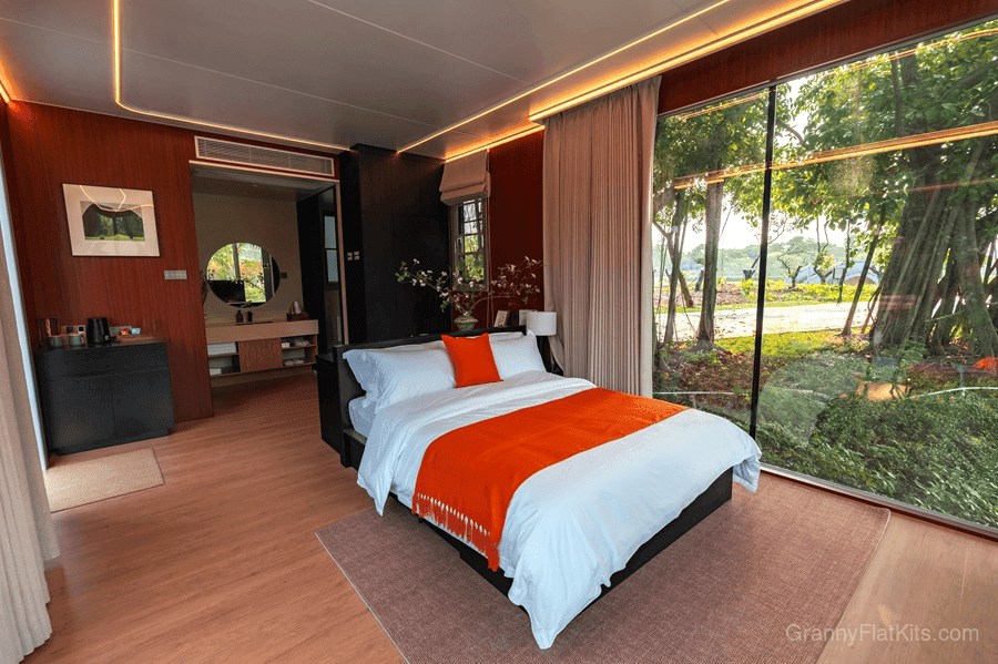 Bedroom interior with king-size bed, panoramic glass wall with garden view, and ensuite bathroom